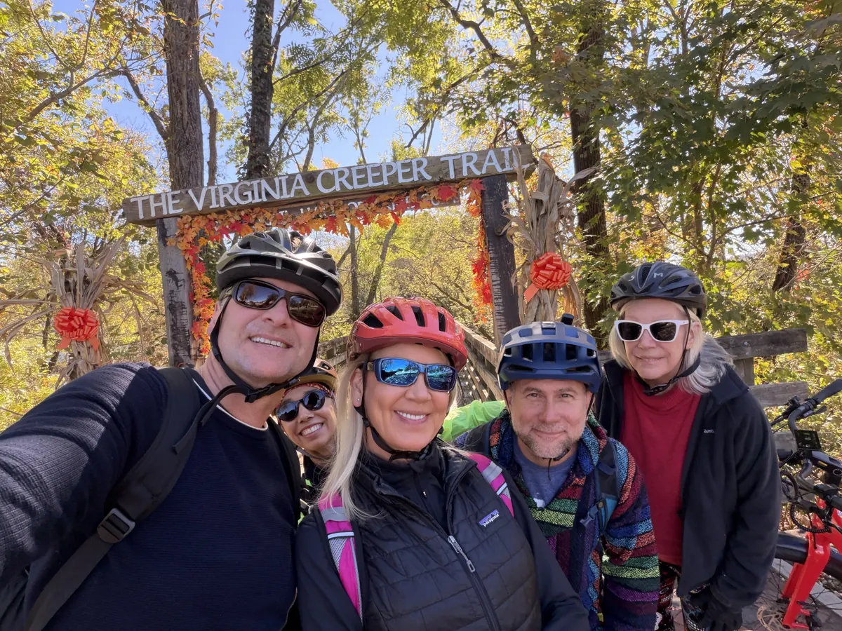 Troy Norton and friends with their bike helmets on at the Virginia Creeper Trail entrance sign in the fall